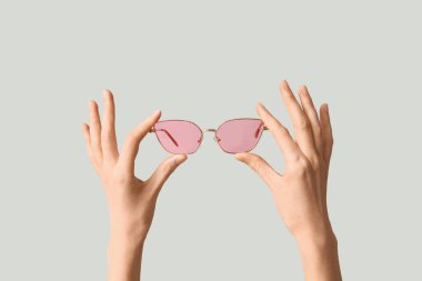 Gri arka plan üzerinde şık güneş gözlüğü ile eller