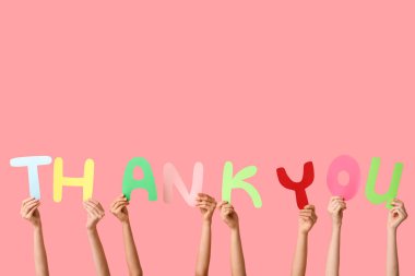 Pembe arka plandaki kağıttan yaptığın teşekkür mesajı tutan kadın elleri.