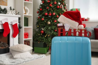 İçinde Noel Baba şapkası, pasaport ve Noel süsü olan çanta oturma odasında.