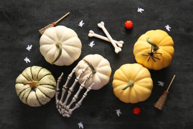 Koyu arkaplanda olgun balkabakları ve Cadılar Bayramı süslemeleri olan kompozisyon