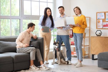 Dizüstü bilgisayarları ve komik köpekleri olan iş arkadaşları ofiste.