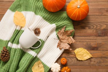 Şık, sıcak süveter, fincan ve ahşap arka planda sonbahar dekoru olan kompozisyon