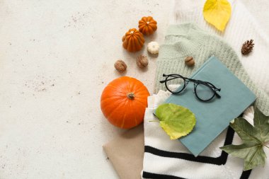 Kitaplı, gözlüklü, kalın kazaklı ve arka planda sonbahar dekorlu kompozisyon