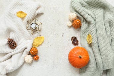 Şık, sıcak süveterler, mumlar ve arka planda sonbahar dekoru olan kompozisyon