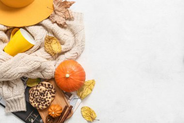 Kalın süveter, kurabiye, balkabağı ve açık arkaplanda sonbahar yapraklarıyla kompozisyon