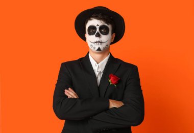 Cadılar Bayramı için giyinmiş genç adam turuncu arka planda