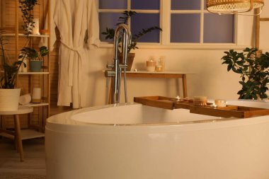 Banyonun içinde küvet, bitkiler ve akşamları yanan mumlar var.