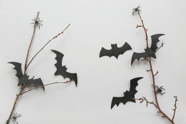 Gri arka planda Cadılar Bayramı için ağaç dalları, kağıt yarasalar ve örümceklerle kompozisyon