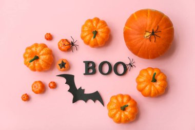 Composition with word BOO and pumpkins for Halloween on pink background clipart