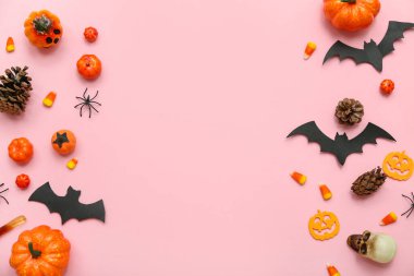Pembe arka planda Cadılar Bayramı için farklı dekorasyon ve şekerler içeren kompozisyon