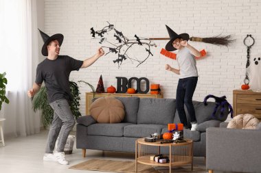 Baba ve oğlu Cadılar Bayramı için giyinmiş evde dans eden büyücüler gibi.