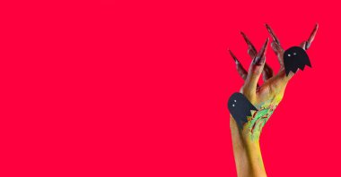 Kırmızı arka planda kağıt hayaletler ve metin için yeri olan cadının eli. Cadılar Bayramı