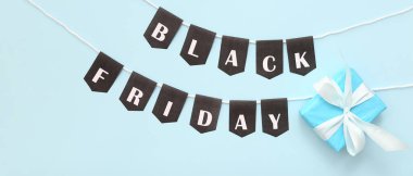 Kara Cuma yazılı çelenk ve açık mavi arka planda hediye