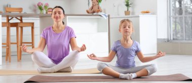 Sportif anne ve küçük kızı mutfakta meditasyon yapıyor.