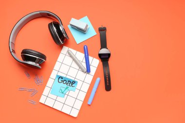 Kırmızı arka planda kelime golü, kırtasiye, kulaklık ve akıllı seğirme ile yapışkan not