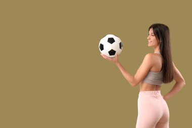Futbol topunun arka planında spor yapan genç bir kadın.