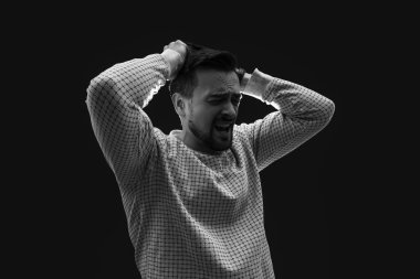 Genç adam siyah arka planda panik atak geçiriyor.