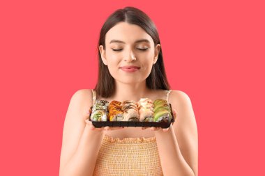 Kırmızı arka planda suşisi olan genç bir kadın, yakın plan.