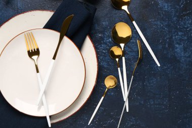 Masa seti, temiz tabaklar ve mavi arkaplanda altın çatal bıçak takımı.