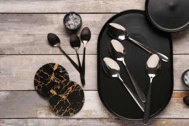 Temiz tabaklar, bir kaşık seti ve aşınmış ahşap masada bardak altlığı.