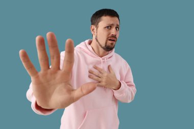 Genç adam mavi arka planda panik atak geçiriyor.