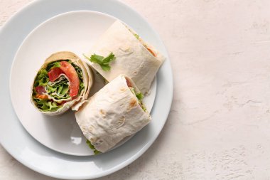 Hafif arka planda domatesli ve yeşillikli lezzetli lavaş ruloları.