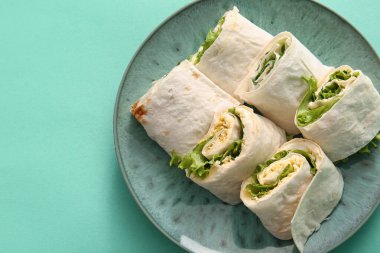 Turkuaz arka planda yumurta ve yeşillikli lezzetli lavaş ruloları.