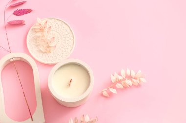 Elinde mum ve pembe arka planda dekoratif podyum olan tutucu