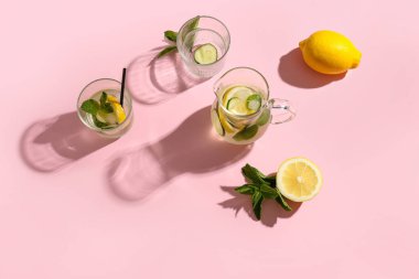 Gözlük ve bir sürahi pembe arka planda salatalıklı limonata.