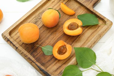 Beyaz ahşap arka planda taze kayısıları olan bir tahta.