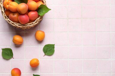 Pembe fayanslı taze kayısıları olan hasır bir kase.