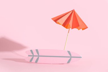 Pembe arkaplanlı mini sörf tahtası.