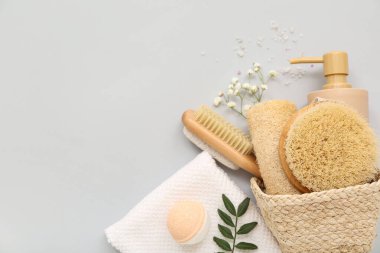 Gri arka planda farklı banyo malzemeleri olan sepet.