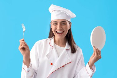 Mavi arka planda çatal ve tabağı olan kadın aşçı.