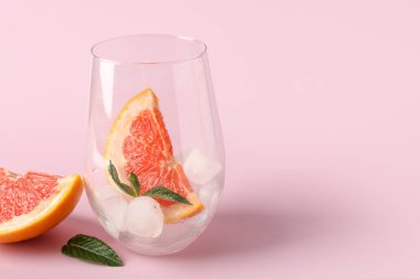 Buzlu bardak, greyfurt ve pembe arkaplanda nane.