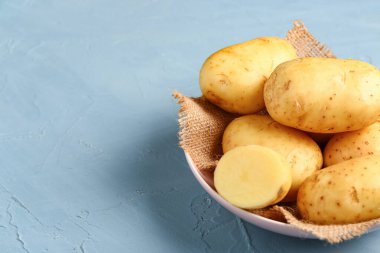 Mavi arka planda çiğ bebek patatesli kase