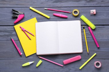 Koyu mavi ahşap arka planda farklı okul kırtasiyesine sahip defterler