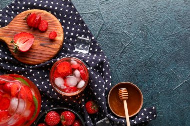 Siyah arka planda çilekli ve ballı bir bardak erimiş su.