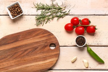 Açık ahşap arka planda kesim tahtası, baharat ve sebzelerle kompozisyon