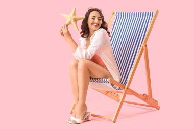 Güverte koltuğunda pembe arka planda deniz yıldızı olan genç bir kadın.