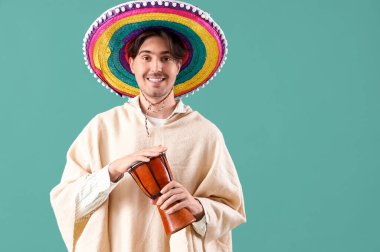 Yeşil arka planda davulu olan genç Meksikalı adam.