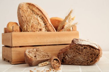 Bej kaplama masa üzerinde farklı taze ekmek ve buğday dikenleriyle dolu bir kutu.