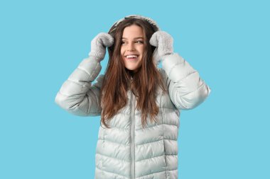 Young woman in winter clothes on blue background