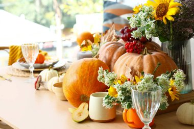 Yemek masasında balkabağı ve çiçeklerle sonbahar ayarı, yakın plan.
