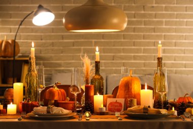 Akşamki Şükran Günü için yanan mumlar, balkabakları ve tebrik kartları olan şenlik masası.