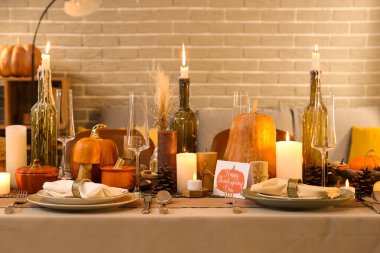 Akşamki Şükran Günü yemeği için yanan mumlar, balkabakları ve tebrik kartları olan güzel bir masa.
