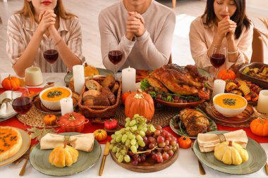 Şükran Günü 'nde şenlik masasında dua eden bir grup genç arkadaş.