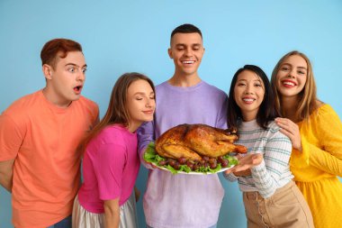 Mavi arka planda lezzetli hindi olan bir grup genç arkadaş. Şükran Günü kutlaması