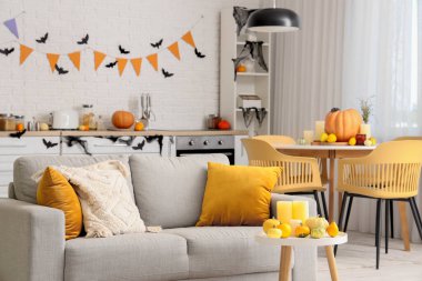 Cadılar Bayramı için dekore edilmiş hafif mutfağın içi kanepe ve yemek masasıyla süslenmiş.