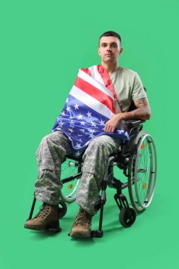 Yeşil arka planda Amerikan bayrağı olan tekerlekli sandalyedeki genç asker. Gaziler Günü kutlamaları